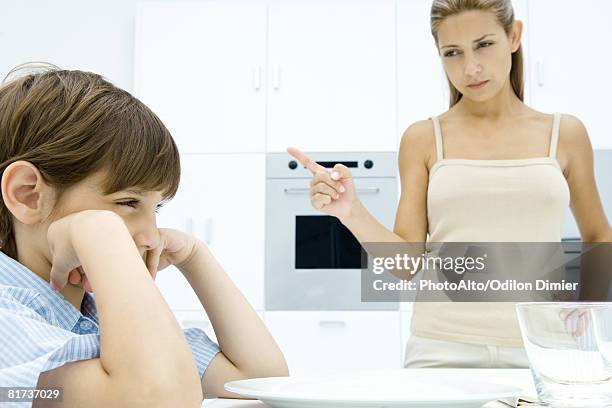 boy pouting at kitchen table, mother shaking her finger - shaking finger stock pictures, royalty-free photos & images