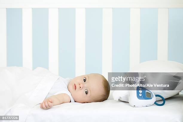 infant lying in crib, looking at camera - babyphone stock-fotos und bilder