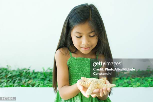 girl holding starfish in hands - starfish holding hands stock pictures, royalty-free photos & images