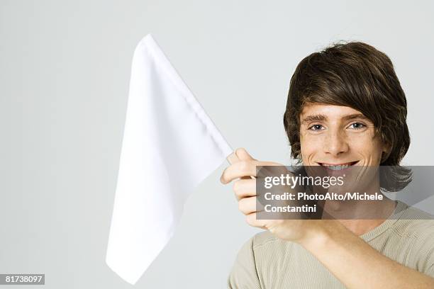 young man holding white flag, smiling at camera - pacifisme stockfoto's en -beelden
