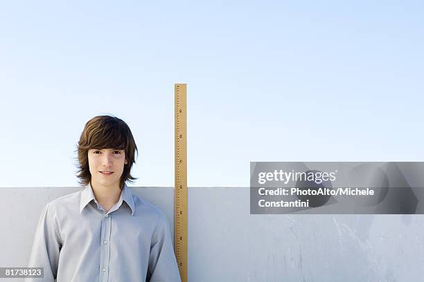 young man standing beside yardstick, smiling at camera - ellen mann stock-fotos und bilder