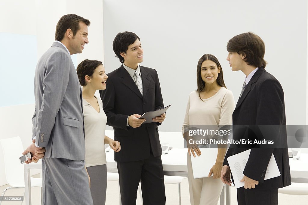 Group of business associates standing together, smiling, chatting