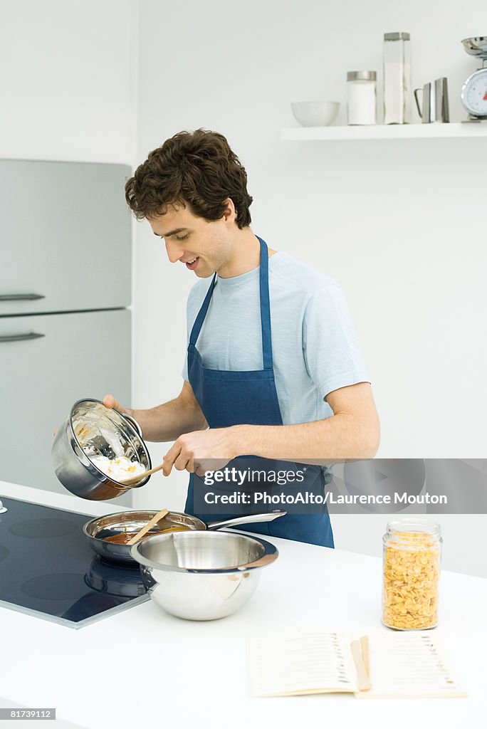 Man standing at stove, preparing food, looking down
