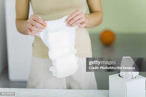 woman holding baby diaper, cropped view - adult diaper stockfoto's en -beelden