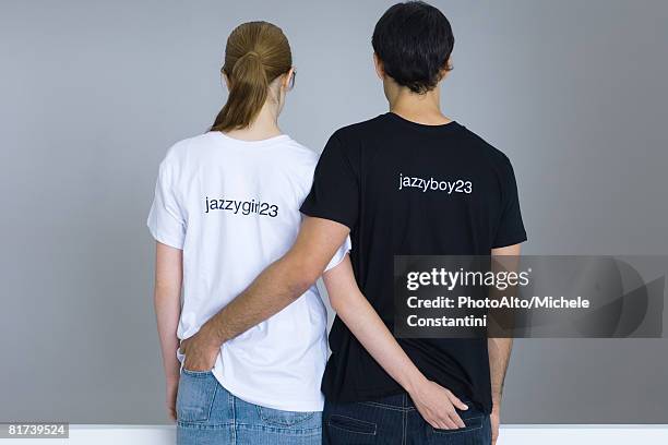 young couple wearing customized tee-shirts, arms around each other's waists, rear view - couple placard stock pictures, royalty-free photos & images