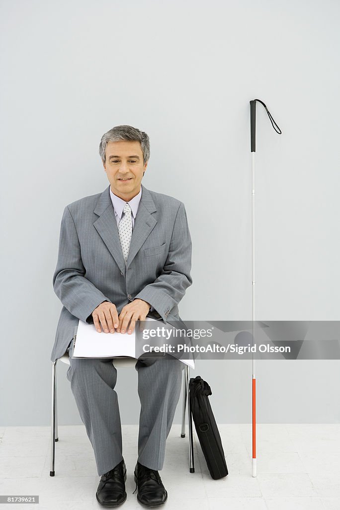 Hombre profesional para personas con dificultades visuales, sentado en una silla de lectura y Br