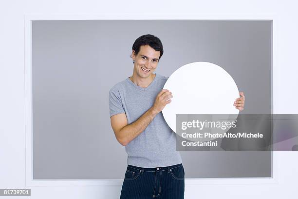 man holding up round sign, smiling at camera - person holding up sign stock-fotos und bilder