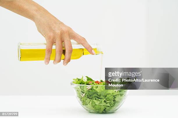 woman pouring olive oil on salad, cropped view of hand - salad bowl stock pictures, royalty-free photos & images