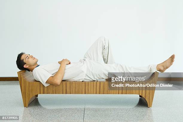 man lying on bench with eyes closed, side view - sitting back foto e immagini stock