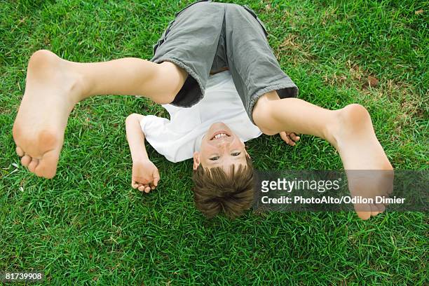 boy lying on the ground with legs in the air, smiling at camera, high angle view - tween heels stock pictures, royalty-free photos & images
