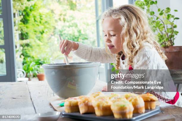 young girl baking in kitchen - cupcakes girls fotografías e imágenes de stock