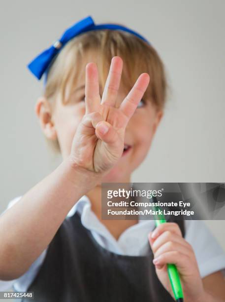 girl holding up three fingers in kitchen - human finger stock pictures, royalty-free photos & images