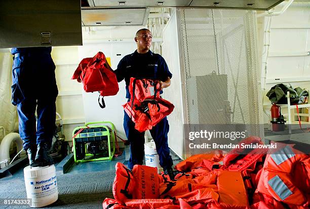 Members of the coast Guard store life jackets in overhead cabinets aboard the Coast Guard cutter Bertholf June 27, 2008 in Baltimore, Maryland. US...