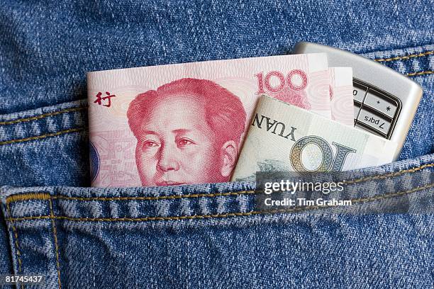 Chinese currency, one hundred and ten Yuan bills, and mobile phone in jeans pocket