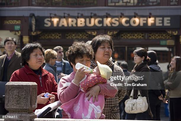 Woman feeds baby outside Starbucks in the Yu Garden Bazaar, China has a one child policy to reduce population