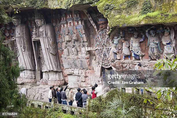 Tourist look at Anicca, God of Destiny holding wheel of life, Dazu rock carvings, Mount Baoding, China