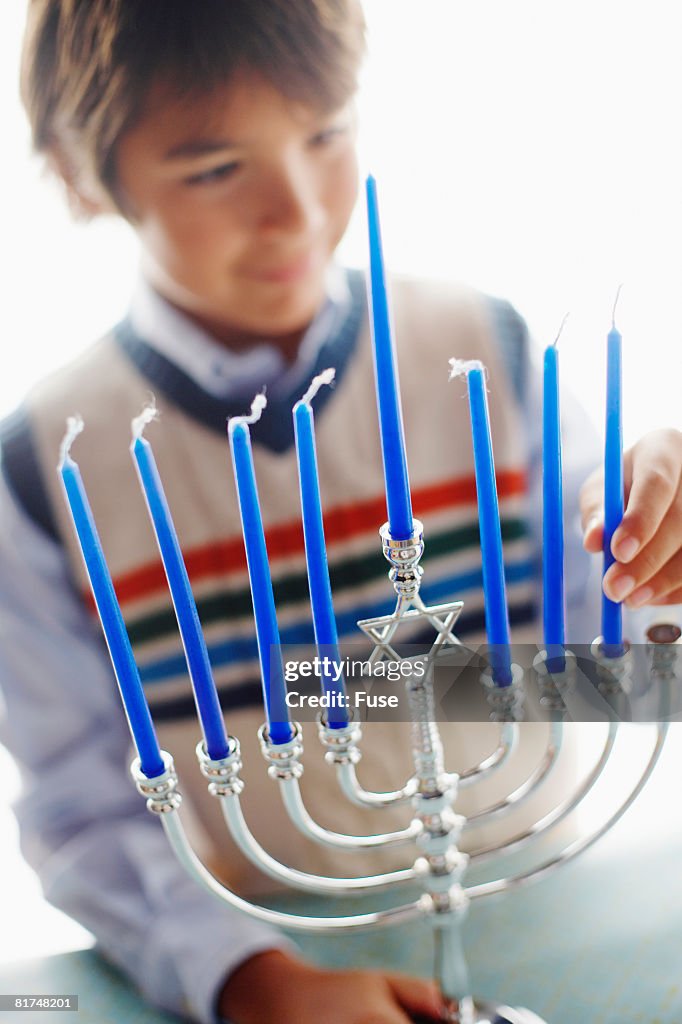 Boy Putting Candle in Menorah