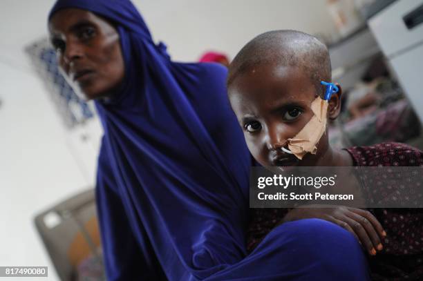 Somali child Safa Mohamed, 3 1/2-years old, is taped with a feeding tube and sits beside her mother Faysa Abdi, as she struggles against acute watery...