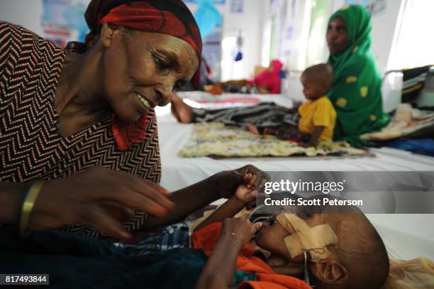 Somali child Nabhan Ismail, 1 1/2 years old, is comforted by his grandmother Ardo Mohamoud after winning a days-long battle against acute watery...