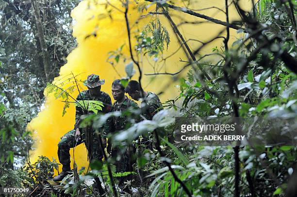 Indonesian soldiers use a smoke grenade to guide rescue helicopters near the crash site of a Casa C-212 plane in the jungle of Salak mountain near...