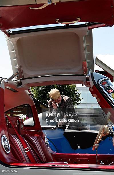 The doors of a 1955 Mercedes-Benz 300SL Gullwing are left open for public inspection as a man looks at a 1955 Morgan Plus 4 at the Brooklands...