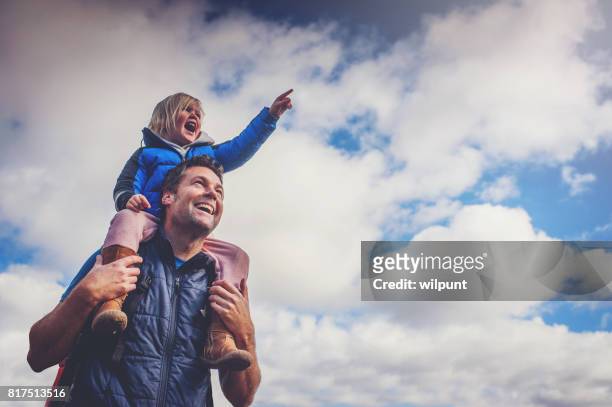 father and daughter pointing cloudy sky - carrying on shoulders stock pictures, royalty-free photos & images