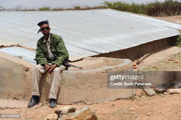 Somali policeman sits beside a traditional cistern for harvesting rainwater, called a berkad, made by the Irish charity Concern-Worldwide as the Horn...