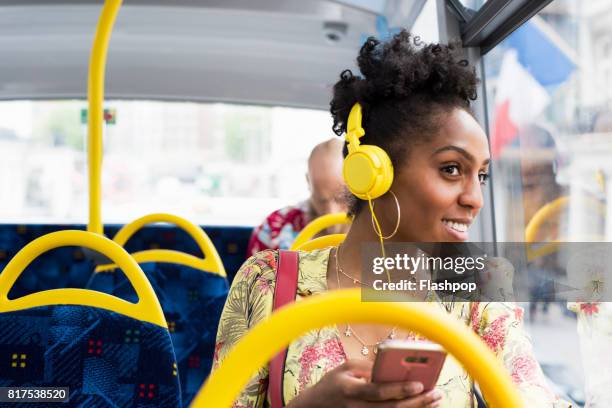 portrait of woman relaxing on a bus wearing headphones - commercial land vehicle stock pictures, royalty-free photos & images