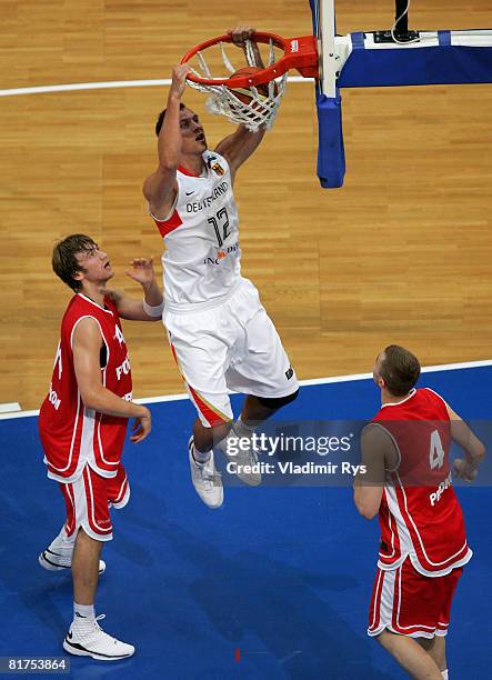 Guido Gruenheid of Germany has a breakaway slam dunk as Pawel Kikowski and Bartloniej Woloszyn of Poland look on during the international friendly...