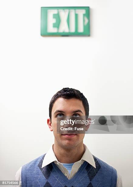 man standing under exit sign - exit sign stock photos et images de collection