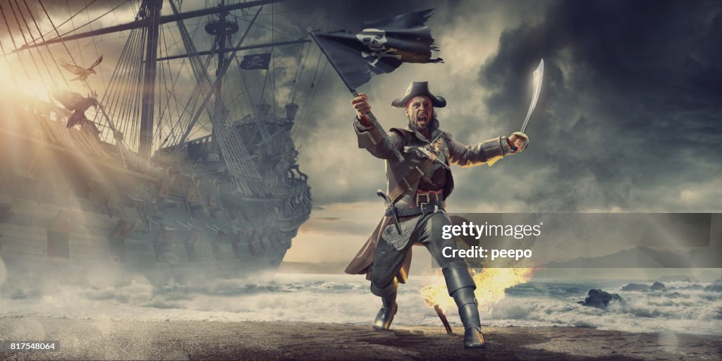 Piraat op strand Holding vlag en Cutlass in de buurt van piratenschip
