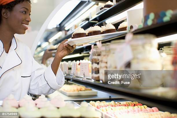 baker putting dessert in display case - cake case stock pictures, royalty-free photos & images