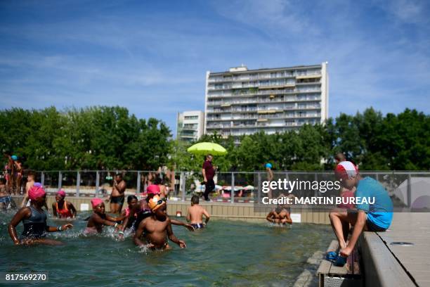 Children swim in a swimming pool at the Bassin de la Villette in Paris on July 18, 2017 as part of the Paris Plages summer event.