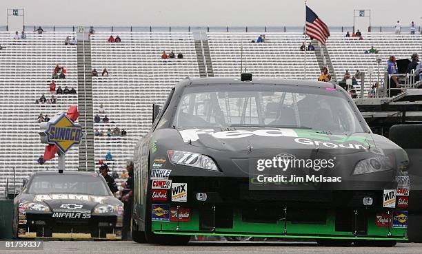 Denny Hamlin, driver of the FedEx Ground Toyota, and Aric Almirola, driver of the U.S. Army Chevrolet drive in the garage area during practice for...