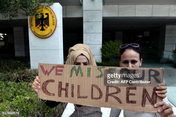 Migrants families holding placards demonstrate outside of the German Consulate in Thessaloniki on July 18, 2017. Migrants complain about delays in...
