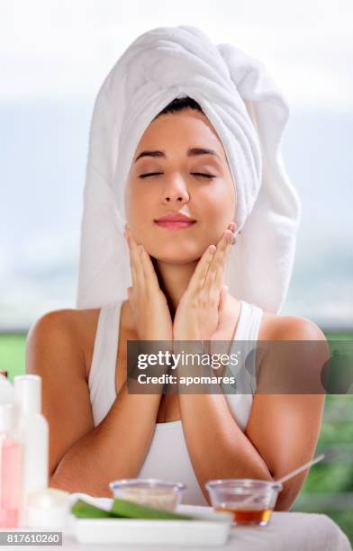 cute and happy hispanic young woman applying aloe vera moisturizer on her face. - aloe vera gel stock pictures, royalty-free photos & images
