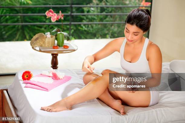 Hispanic young woman using depilation wax on her legs