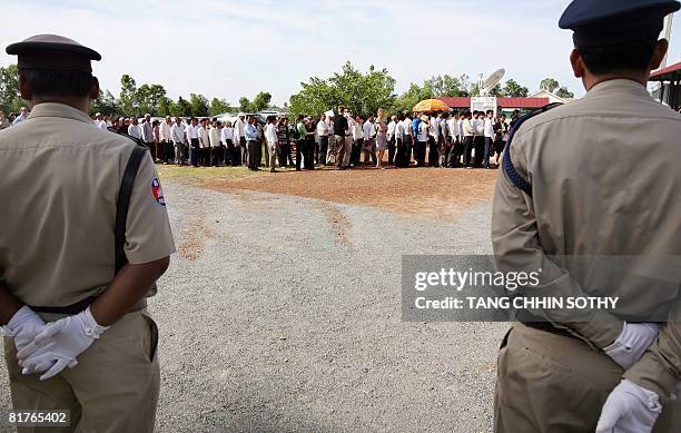 Cambodian security officers stand guard as people line up outside the first public hearing against the detention of former Khmer Rouge deputy prime...