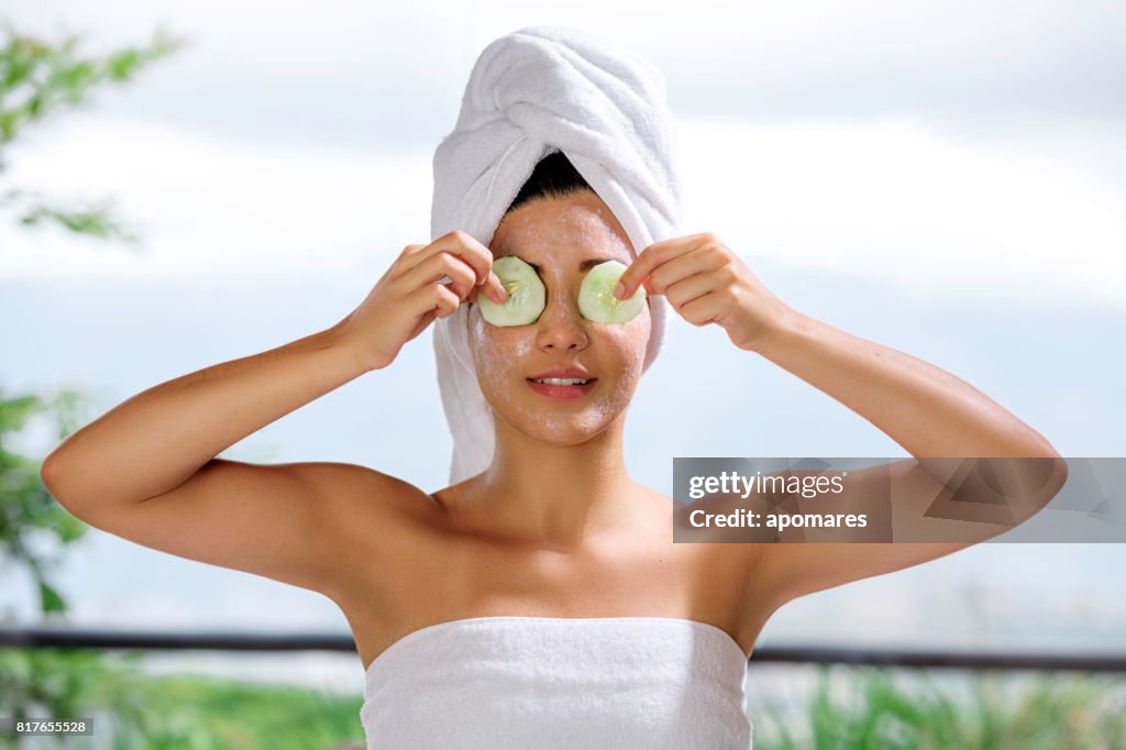 Hisoire jeune femme avec CREME sur des tranches de concombre et de visage sur ses yeux
