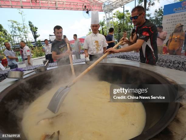 Tourists cook fish with big pot in an eco-leisure garden on July 17, 2017 in Zhangjiajie, Hunan Province of China. Zhangjiajie held an activity on...