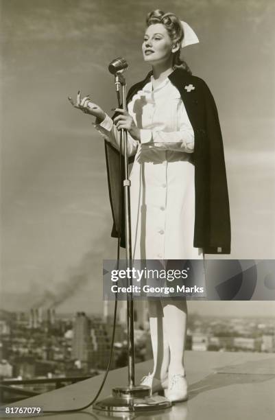 female nurse speaking into microphone on rooftop - microfoonstandaard stockfoto's en -beelden