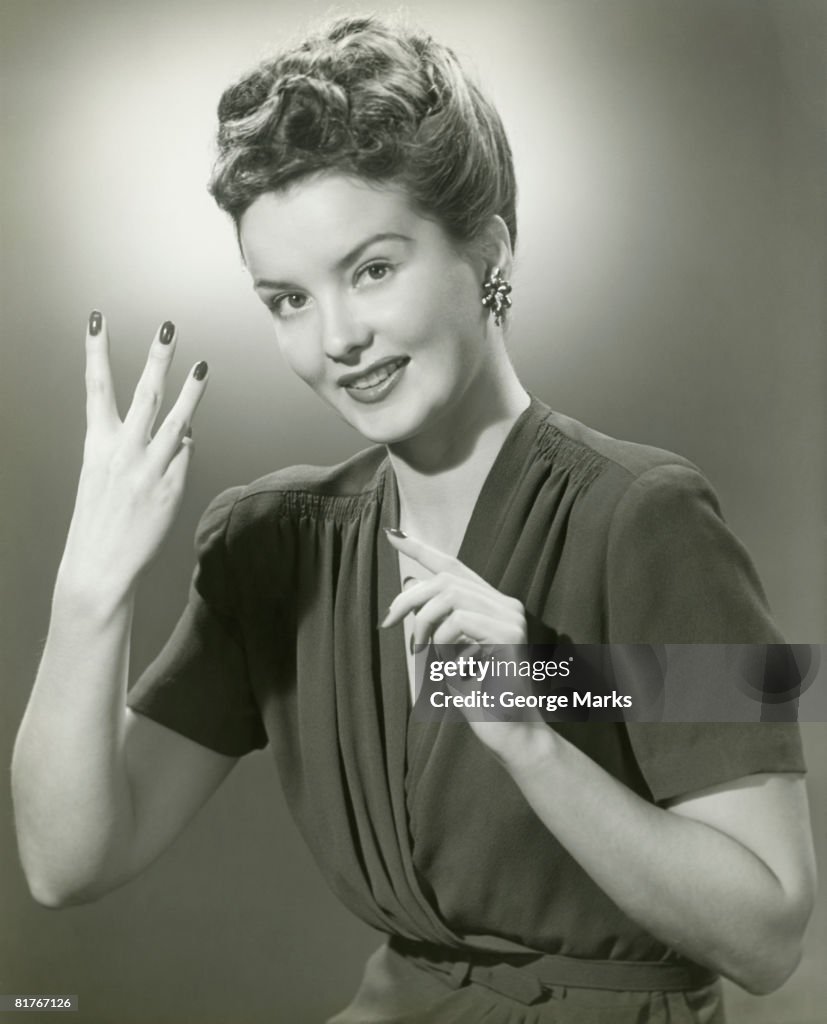 Studio portrait of young woman making hand gesture