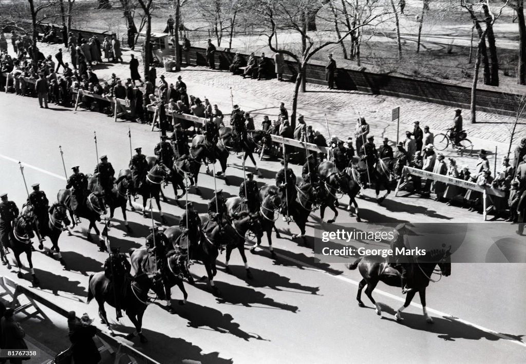 Parade on urban street including soldiers on horses