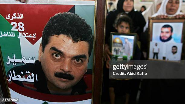 Palestinians hold photos of their relatives as a man displays one of Lebanese prisoner in Israeli jail, Samir Kantar , during a protest calling for...