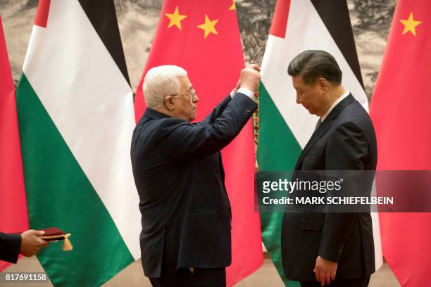 Palestinian President Mahmoud Abbas presents a medallion to Chinese President Xi Jinping during a signing ceremony at the Great Hall of the People in...
