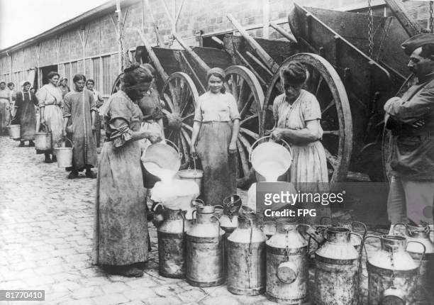Women war workers filling churns with milk at a distribution centre outside Paris, France, circa 1916.