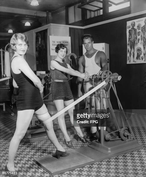 Bodybuilder Charles Atlas demonstrates the Electric Vibrator, an innovative aid to muscle development, to Miss Beth Milton, circa 1930.