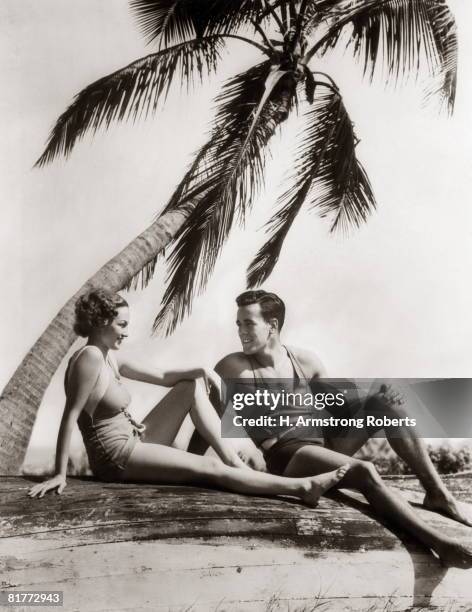 smiling couple man woman under palm tree bathing suits florida. - fotos años 20 fotografías e imágenes de stock