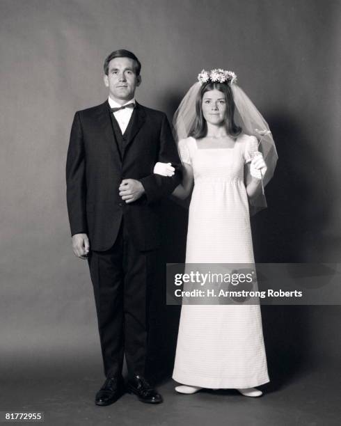 full-length portrait of groom arm-in-arm with bride with daisy veil. - vintage wedding stock-fotos und bilder
