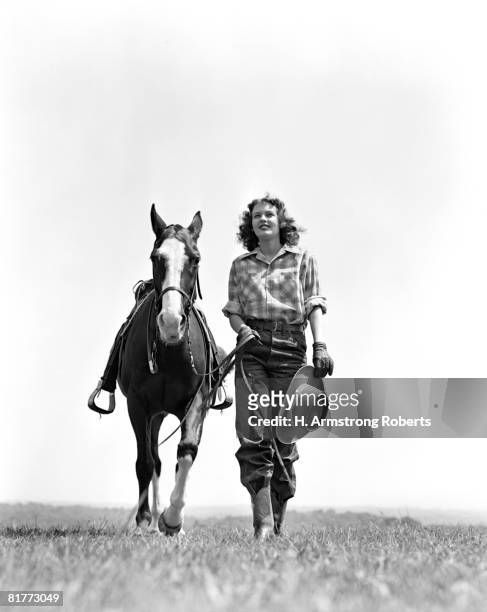 woman walking beside horse holding cowboy hat in gloved hand fashion cowgirl western head on. - cowgirl stock-fotos und bilder